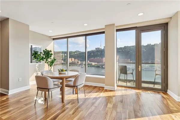a dining room with wooden floor and a floor to ceiling window