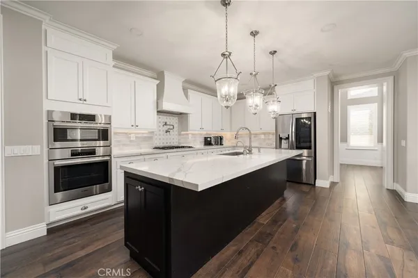 a large kitchen with kitchen island white cabinets and stainless steel appliances