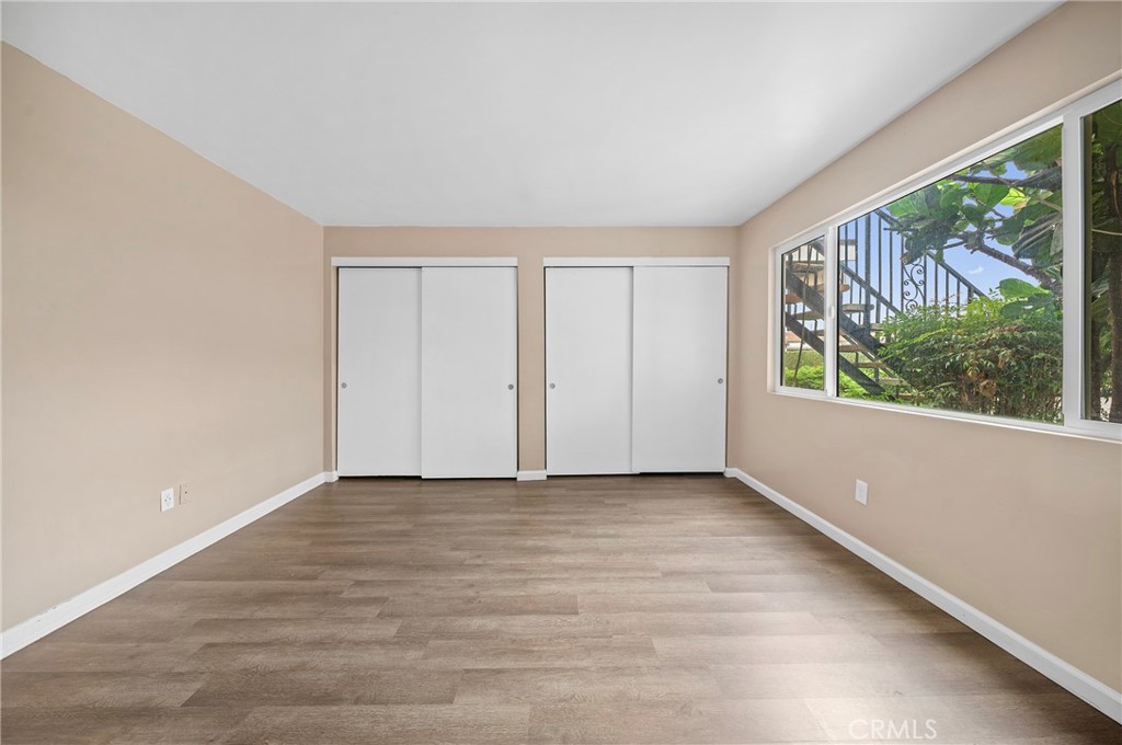1192 Mitchell Avenue, Unit 70 Tustin, CA 92780 - Photo 11 of 29 a view of an empty room with wooden floor and a window