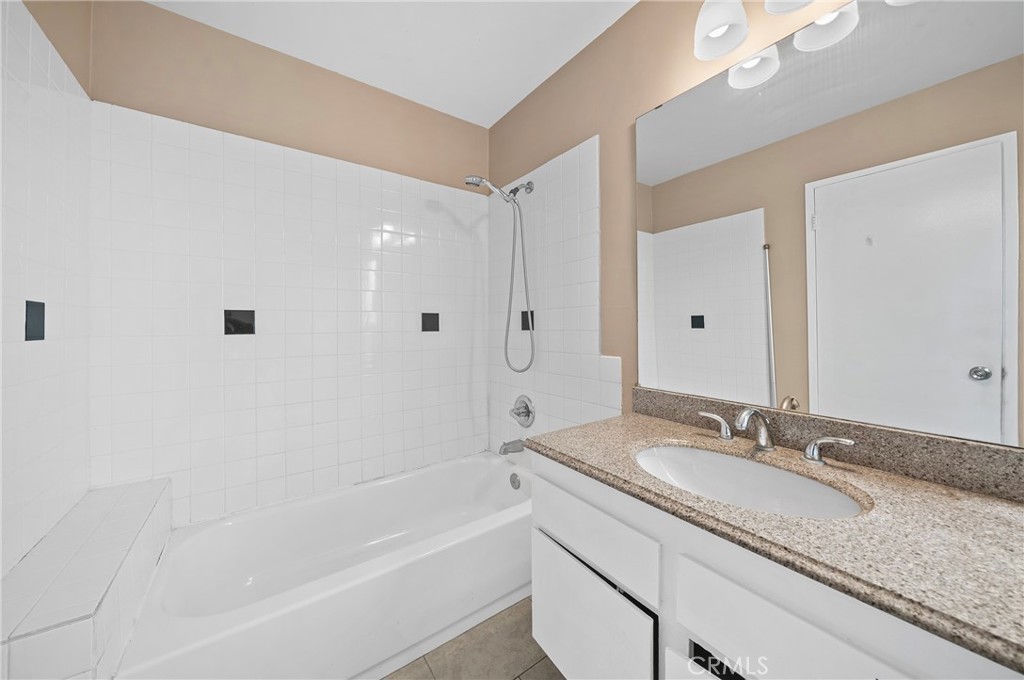 1192 Mitchell Avenue, Unit 70 Tustin, CA 92780 - Photo 15 of 29 a bathroom with a granite countertop sink a mirror and a bathtub