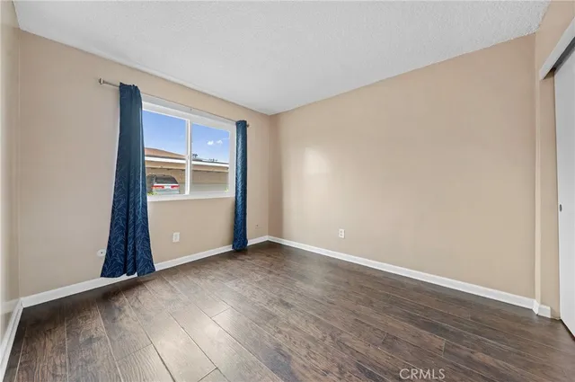 an empty room with wooden floor closet and windows
