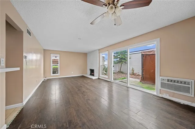 an empty room with wooden floor fan and windows