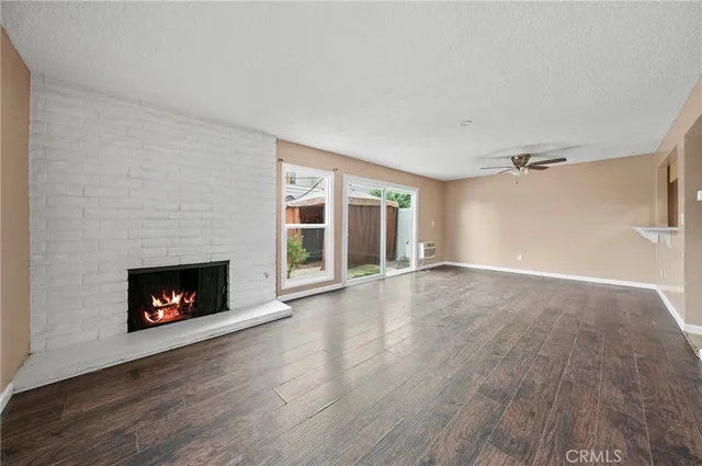 a view of an empty room with wooden floor fireplace and a window