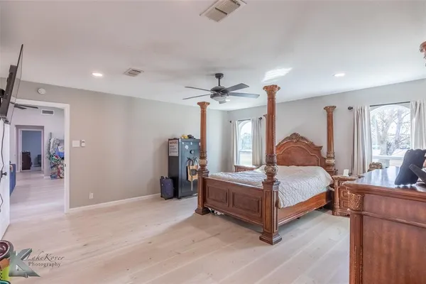 a spacious bedroom with a bed chandelier and a window