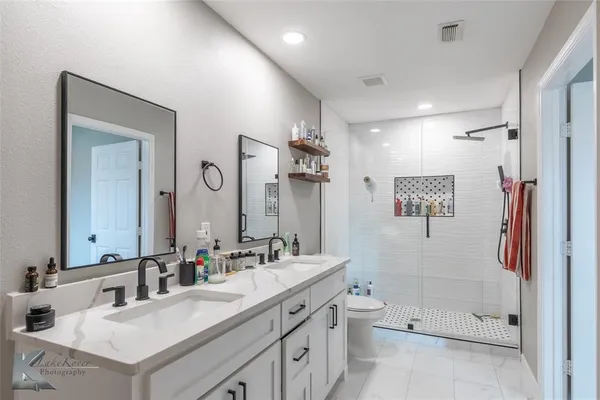a bathroom with a double vanity sink toilet mirror and bathtub