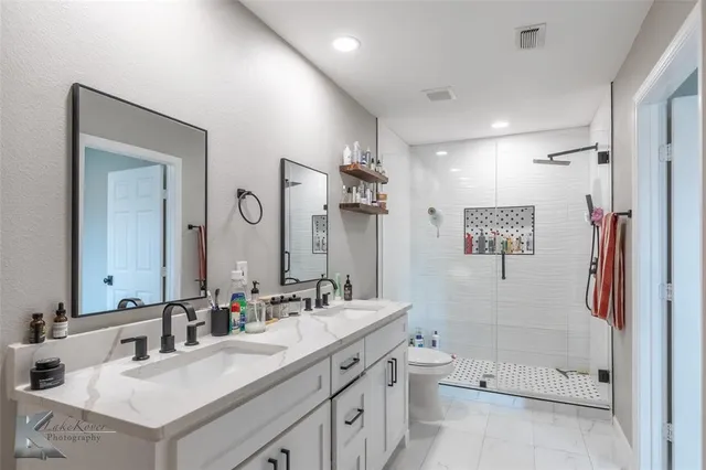 a bathroom with a double vanity sink toilet mirror and bathtub
