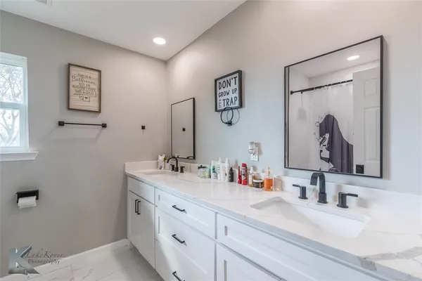 a bathroom with double vanity sinks a toilet and a mirror