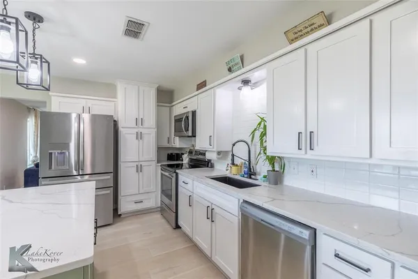 a kitchen with stainless steel appliances granite countertop a refrigerator sink and stove