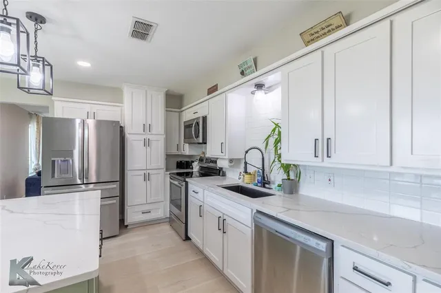 a kitchen with stainless steel appliances granite countertop a refrigerator sink and stove