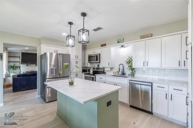 a kitchen with stainless steel appliances granite countertop a sink a stove and a refrigerator