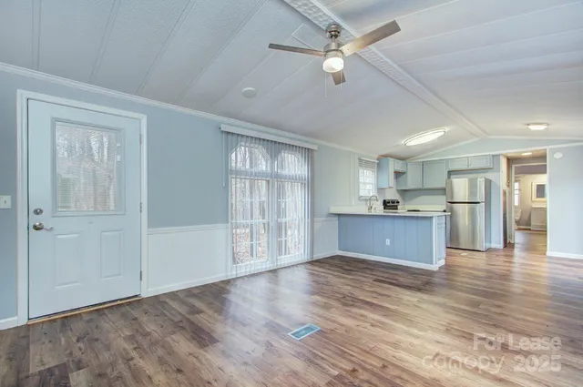 an empty room with wooden floor cabinet and windows