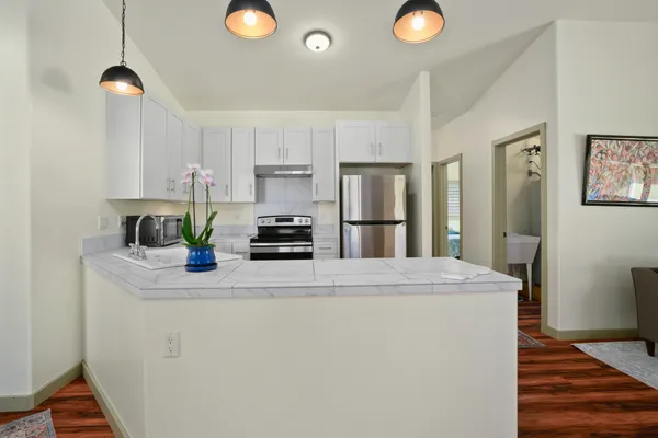 a kitchen with stainless steel appliances granite countertop a refrigerator a stove a sink dishwasher and white cabinets with wooden floor