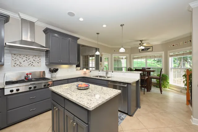 a kitchen with stainless steel appliances granite countertop a sink stove refrigerator and cabinets