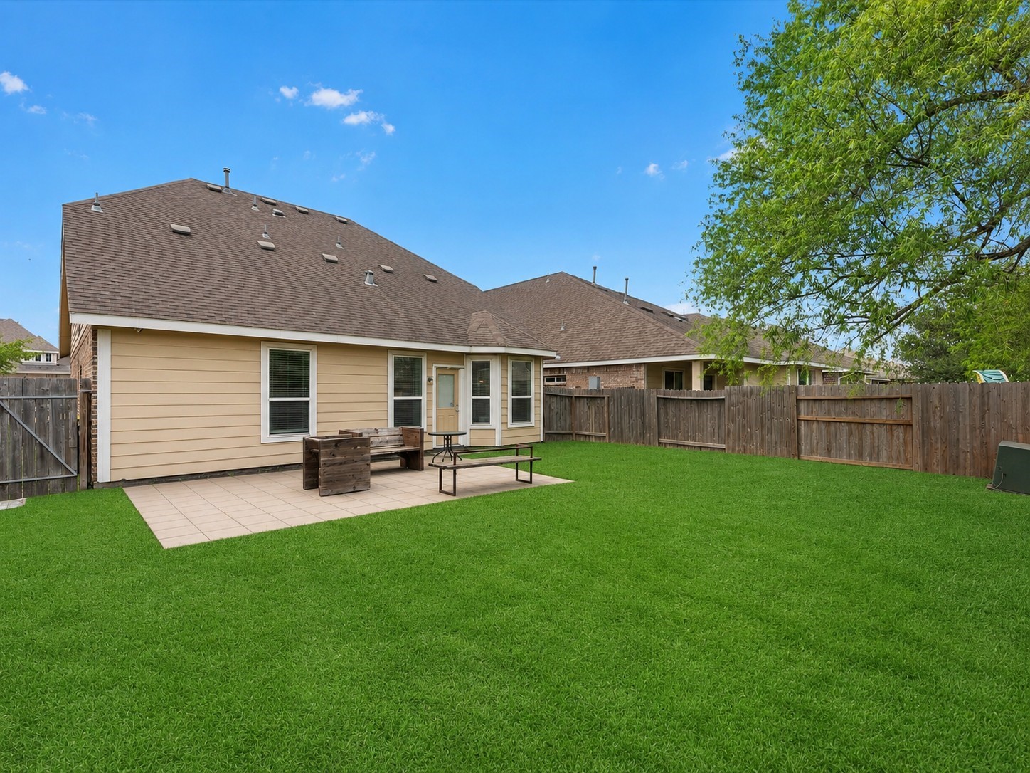 21554 Rainfall Park Drive Spring, TX 77388 - Photo 27 of 33 Spacious backyard with a well-maintained lawn, a patio area, and a wooden fence for privacy.