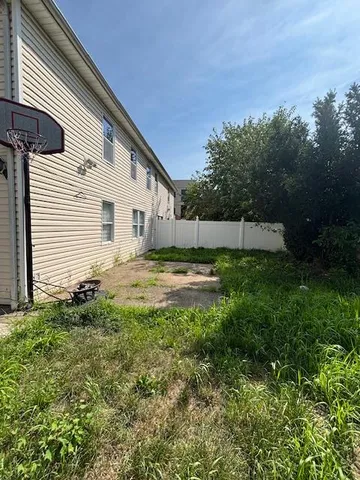 a view of a backyard with plants and large tree