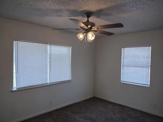 an empty room with windows and fan