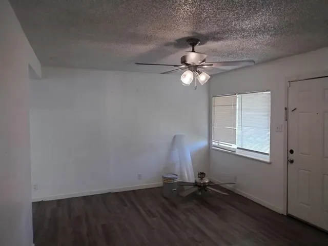 an empty room with wooden floor fan and windows