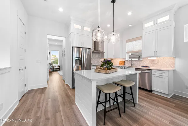 a kitchen with a table chairs refrigerator and wooden floor