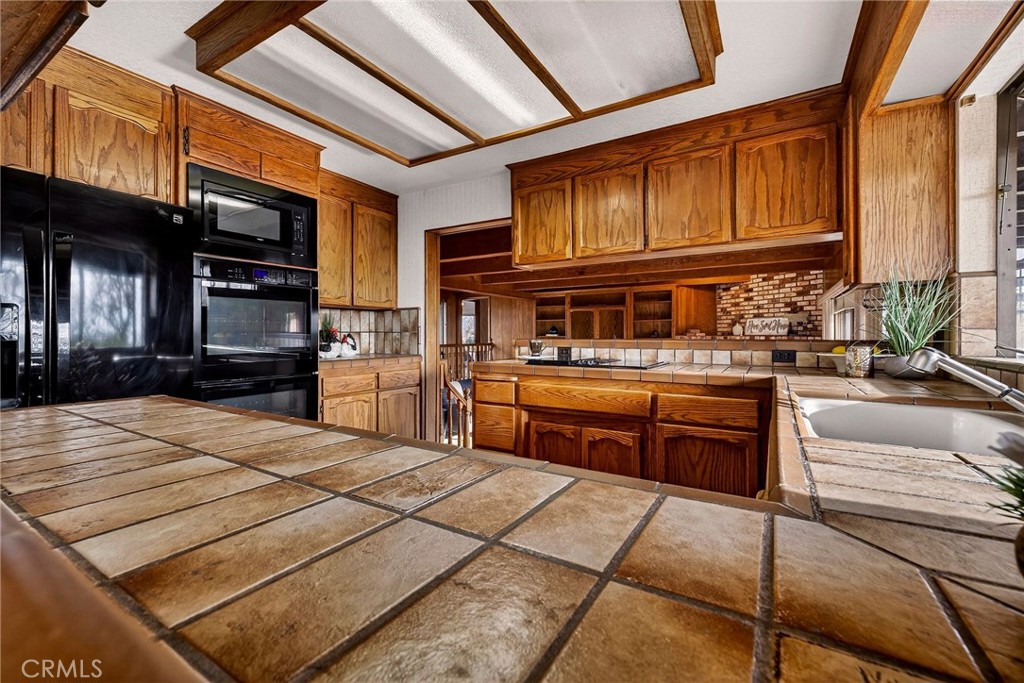 4139 Hidden Valley Road Butte Valley, CA 95965 - Photo 12 of 75 a kitchen with stainless steel appliances kitchen island granite countertop a refrigerator a stove and a sink with wooden cabinets