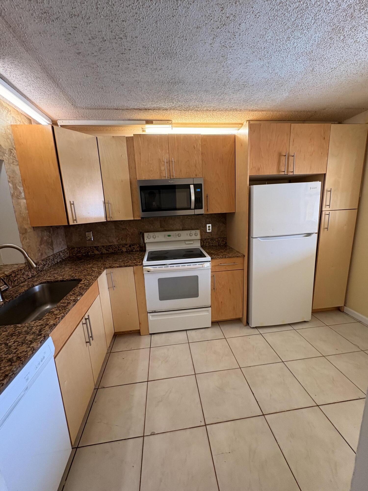 2925 Southwest 22nd Avenue, Unit 202 Delray Beach, FL 33445 - Photo 4 of 14 a kitchen with a stove a refrigerator and a sink