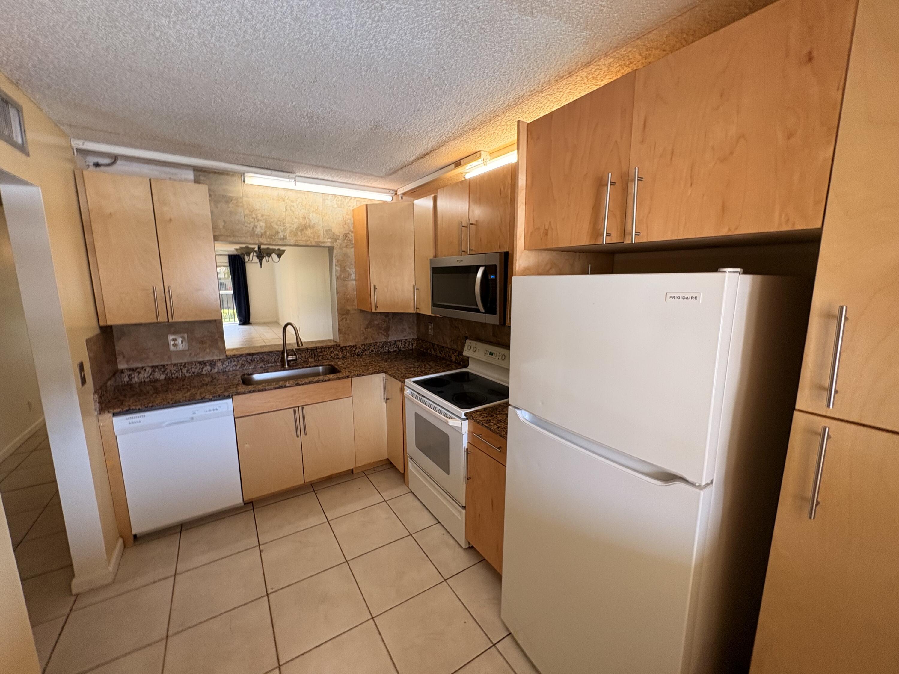 2925 Southwest 22nd Avenue, Unit 202 Delray Beach, FL 33445 - Photo 6 of 14 a kitchen with a sink a refrigerator and cabinets
