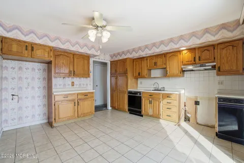 a large kitchen with stainless steel appliances a stove a sink dishwasher and a refrigerator with white cabinets