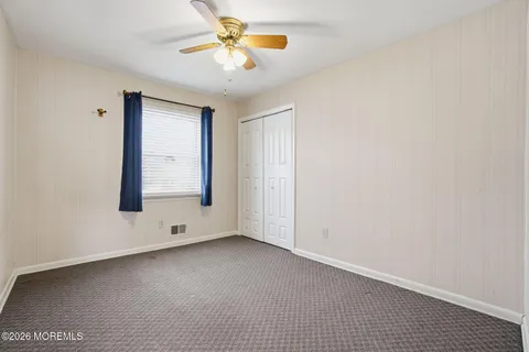 an empty room with windows and fan
