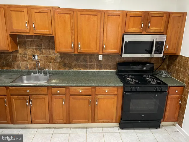 a kitchen with granite countertop a stove top oven microwave and cabinets
