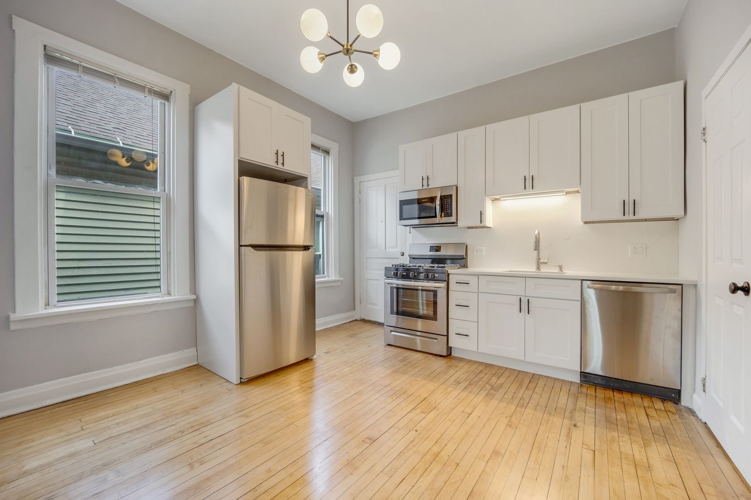 1346 West Webster Avenue, Unit 2F Chicago, IL 60614 - Photo 2 of 12 a kitchen with granite countertop a refrigerator a sink dishwasher a stove and white cabinets with wooden floor