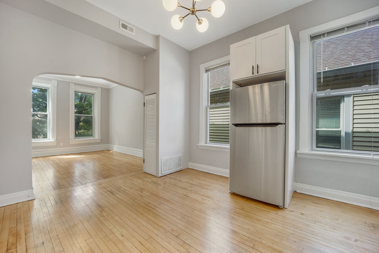 1346 West Webster Avenue, Unit 2F Chicago, IL 60614 - Photo 3 of 12 an empty room with wooden floor a ceiling fan and windows