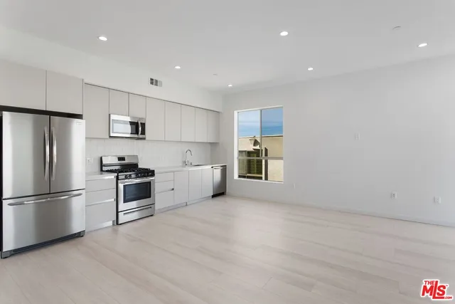 a large white kitchen with a refrigerator a stove a sink a microwave and cabinets