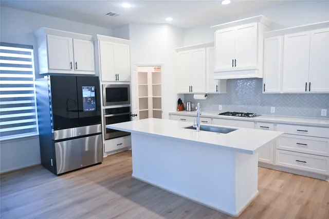a kitchen with stainless steel appliances a stove refrigerator and cabinets