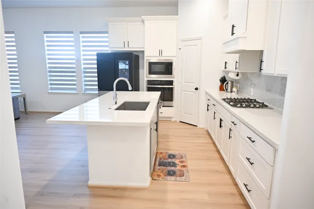 a kitchen with stainless steel appliances kitchen island wooden cabinets a stove a sink and a refrigerator