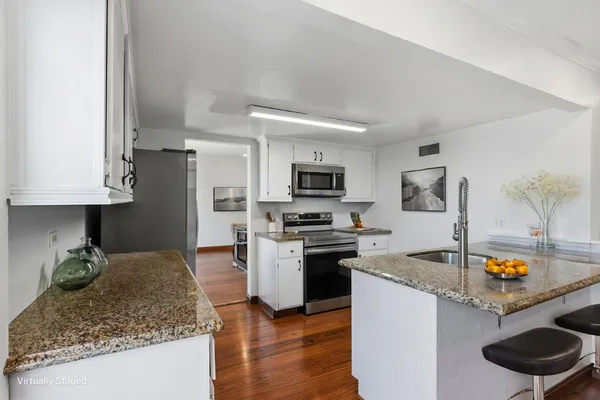 a kitchen with stainless steel appliances granite countertop a sink dishwasher stove top oven and refrigerator with wooden floor