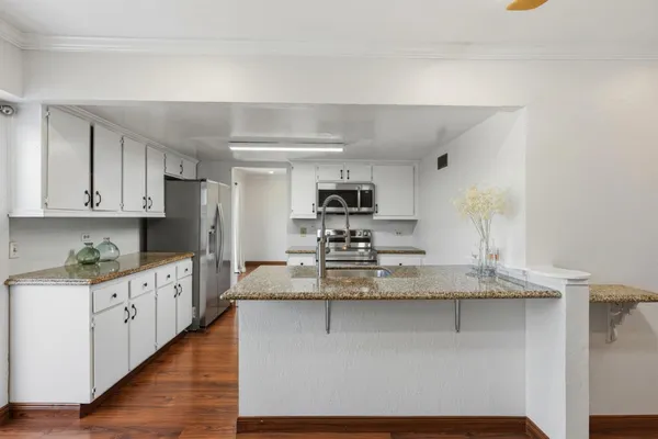 a kitchen with kitchen island granite countertop a sink cabinets and stainless steel appliances