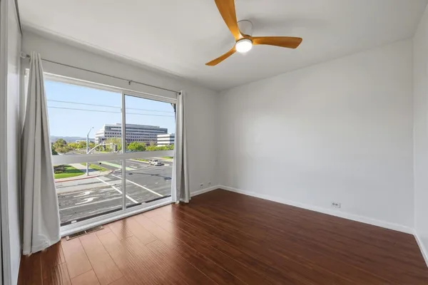 a view of an empty room with wooden floor and a window