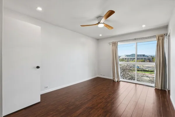 an empty room with wooden floor fan and windows