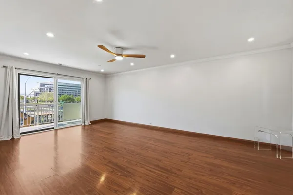 an empty room with wooden floor and a floor to ceiling window