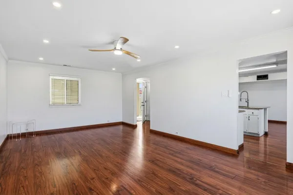 a view of an empty room with a window and wooden floor