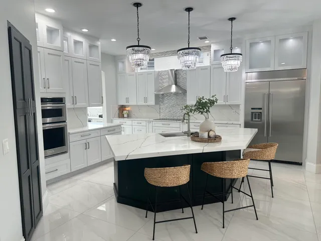 a kitchen with stainless steel appliances kitchen island granite countertop a dining table chairs and white cabinets