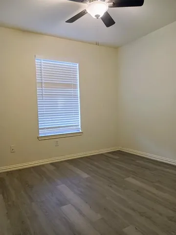 an empty room with a window and a ceiling fan