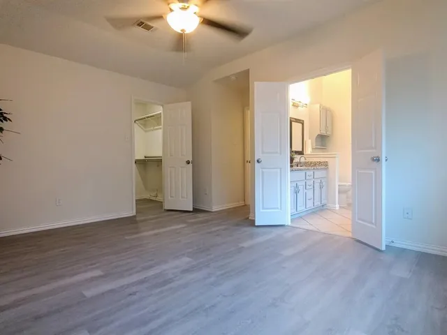 an empty room with wooden floor and a ceiling fan