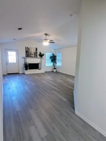 a view of a livingroom with wooden floor a fireplace and window