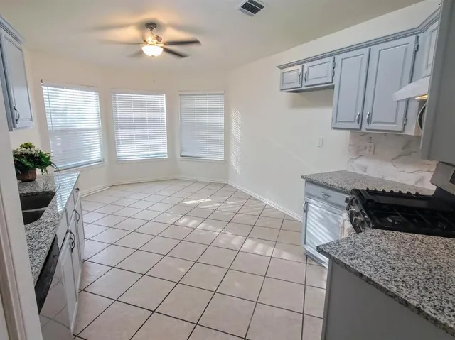 a kitchen with stainless steel appliances granite countertop a stove a sink a dining table and chairs