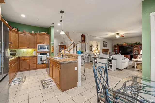a kitchen with stainless steel appliances kitchen island granite countertop a table chairs and a refrigerator