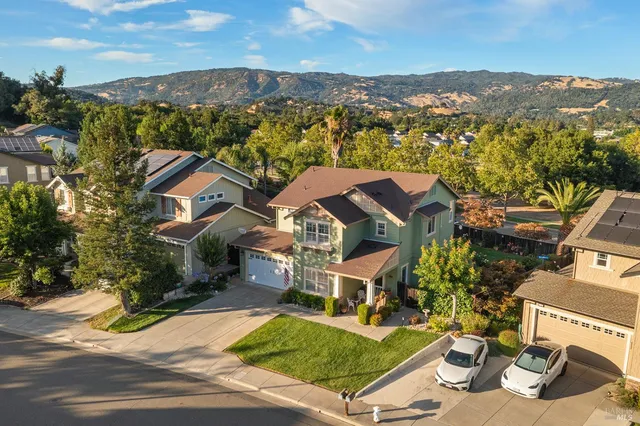 a view of a big house with a big yard and large trees