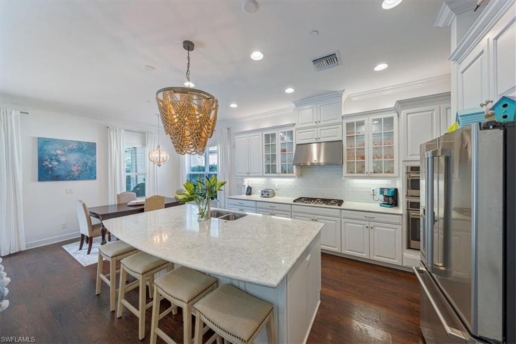 23734 Pebble Pointe Lane Estero, FL 34135 - Photo 4 of 34 a kitchen with stainless steel appliances granite countertop a stove refrigerator a table and chairs