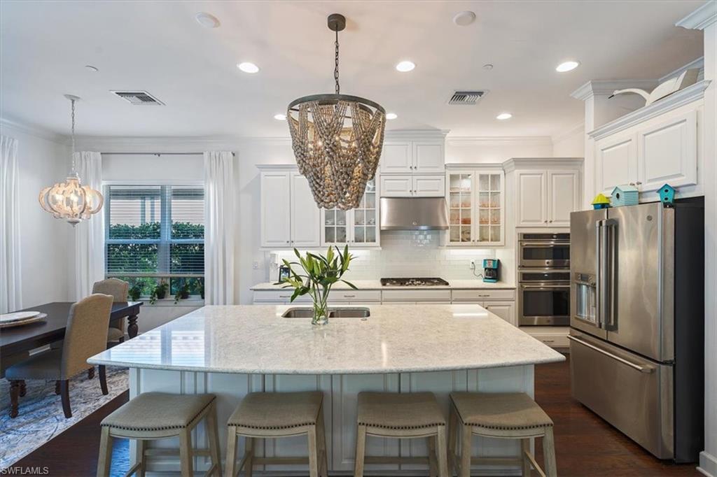 23734 Pebble Pointe Lane Estero, FL 34135 - Photo 5 of 34 a kitchen with stainless steel appliances a dining table chairs and refrigerator