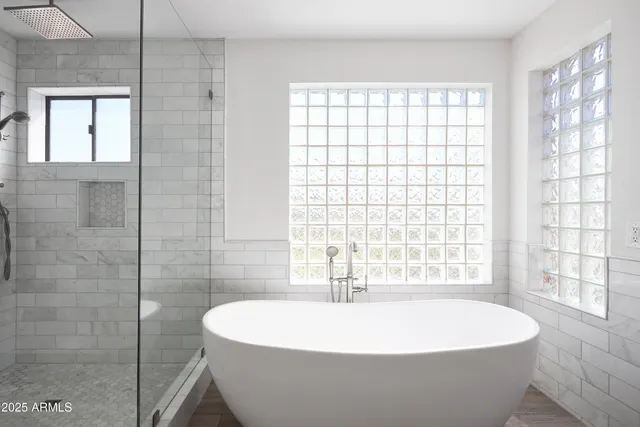 a white bath tub sitting in a bathroom next to a window