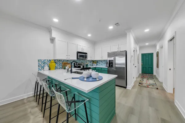 a kitchen with a dining table cabinets appliances and wooden floor